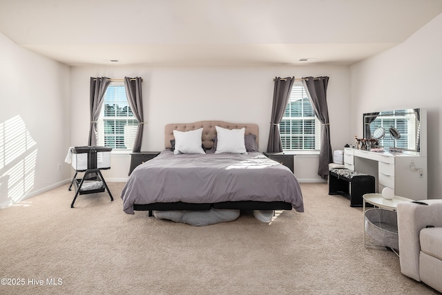 bedroom featuring light colored carpet and multiple windows