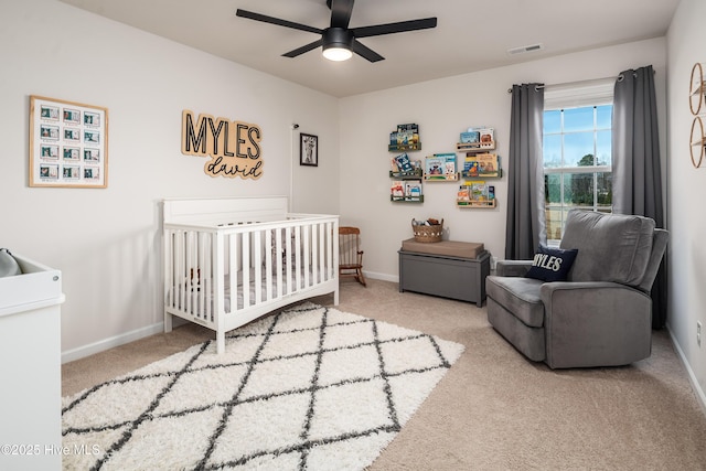 bedroom featuring ceiling fan, carpet flooring, and a crib