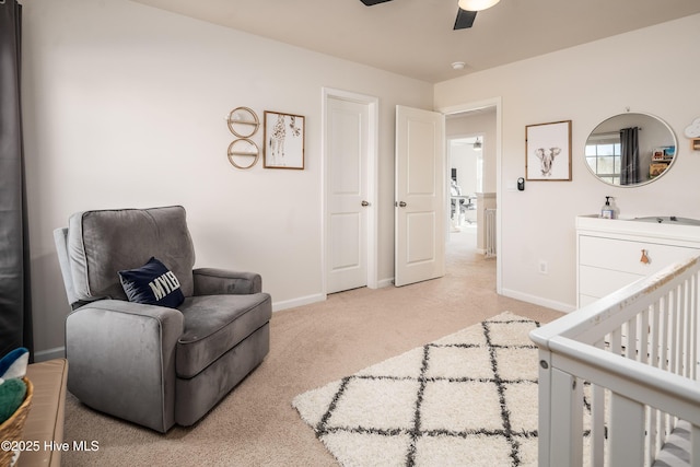 bedroom featuring a crib, light carpet, and ceiling fan