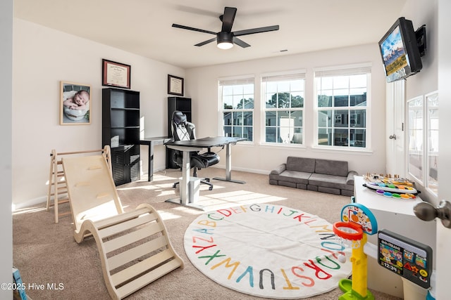 carpeted office space with ceiling fan