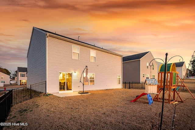 back house at dusk with a lawn and a playground