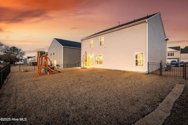 back house at dusk featuring a yard and a playground