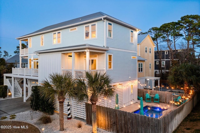 back house at dusk featuring a patio and a swimming pool