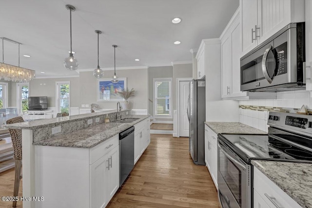 kitchen featuring a sink, white cabinetry, a kitchen breakfast bar, hanging light fixtures, and appliances with stainless steel finishes