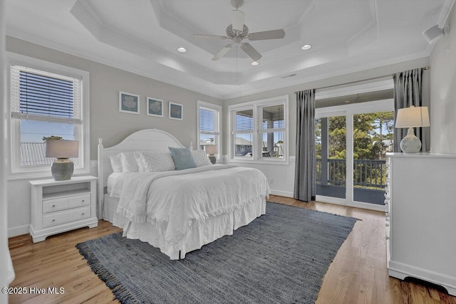 bedroom with baseboards, access to outside, a tray ceiling, crown molding, and light wood-style floors