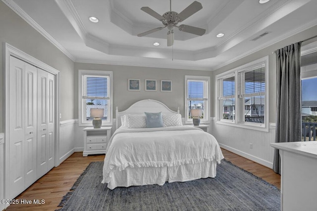 bedroom featuring multiple windows, visible vents, and a tray ceiling