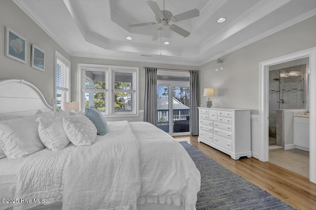 bedroom featuring ensuite bathroom, light wood-style flooring, access to exterior, ornamental molding, and a raised ceiling