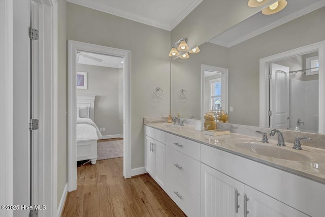 ensuite bathroom featuring a sink, ornamental molding, connected bathroom, and wood finished floors