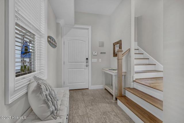 foyer entrance featuring stairway and baseboards