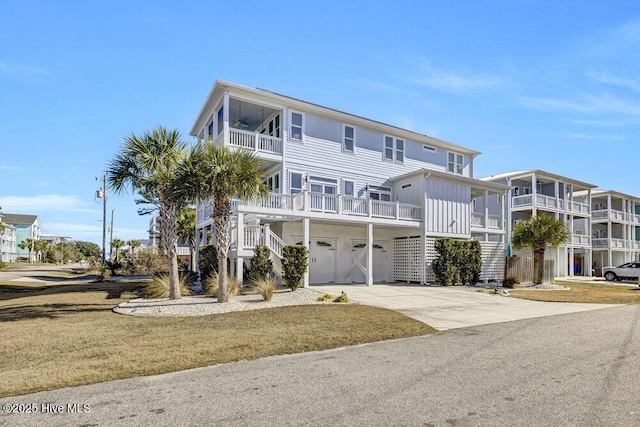 beach home with driveway, a front lawn, stairway, and a balcony