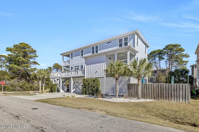 raised beach house featuring driveway, a garage, stairs, fence, and board and batten siding