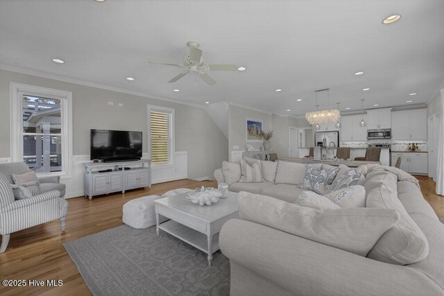 living room featuring ceiling fan, light hardwood / wood-style flooring, ornamental molding, and a healthy amount of sunlight