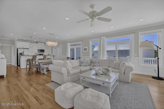 living room featuring ornamental molding, ceiling fan, and light hardwood / wood-style flooring