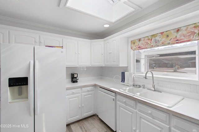 kitchen featuring white appliances, a sink, white cabinetry, and tasteful backsplash