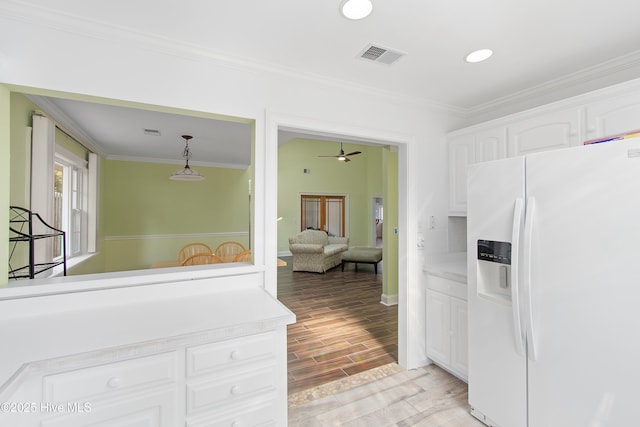 kitchen featuring visible vents, wood tiled floor, light countertops, white fridge with ice dispenser, and white cabinetry