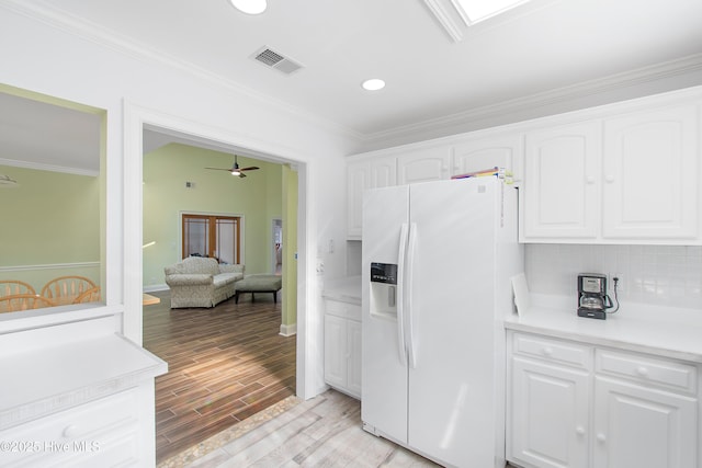 kitchen with white cabinets, decorative backsplash, ornamental molding, light wood-style floors, and white fridge with ice dispenser