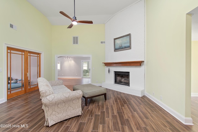 living area with wood finish floors, a brick fireplace, visible vents, and baseboards