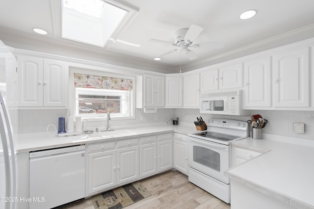 kitchen with white appliances, a sink, and white cabinets