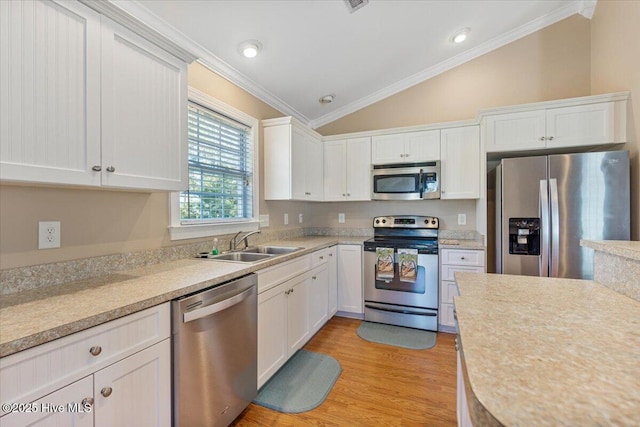 kitchen with white cabinetry, lofted ceiling, sink, ornamental molding, and stainless steel appliances