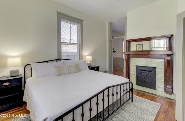 bedroom featuring wood-type flooring and a fireplace