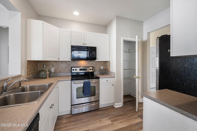 kitchen featuring white cabinetry, sink, backsplash, black appliances, and light wood-type flooring