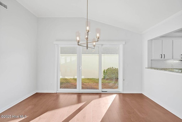 unfurnished dining area featuring lofted ceiling, a notable chandelier, and wood-type flooring