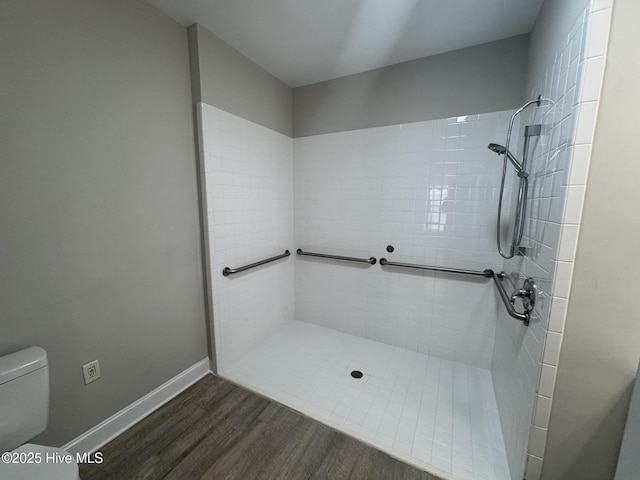 bathroom with hardwood / wood-style flooring, tiled shower, and toilet