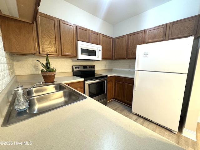 kitchen with tasteful backsplash, sink, white appliances, and light hardwood / wood-style floors