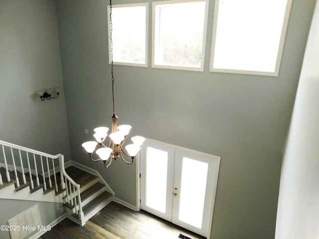 entrance foyer featuring baseboards, a chandelier, stairway, wood finished floors, and french doors