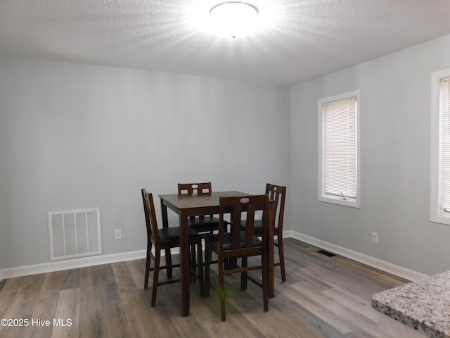 dining room featuring wood-type flooring and a textured ceiling