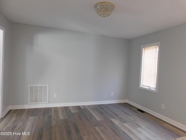empty room with wood finished floors, baseboards, and visible vents