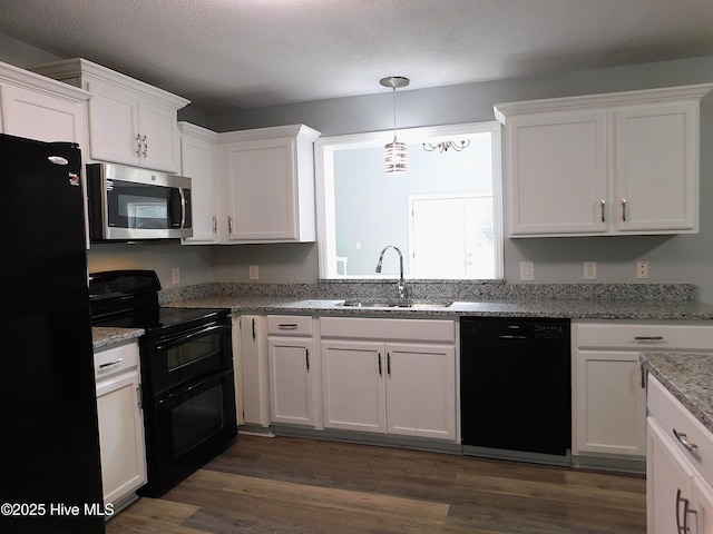 kitchen featuring dark wood-type flooring, white cabinetry, black appliances, a sink, and decorative light fixtures