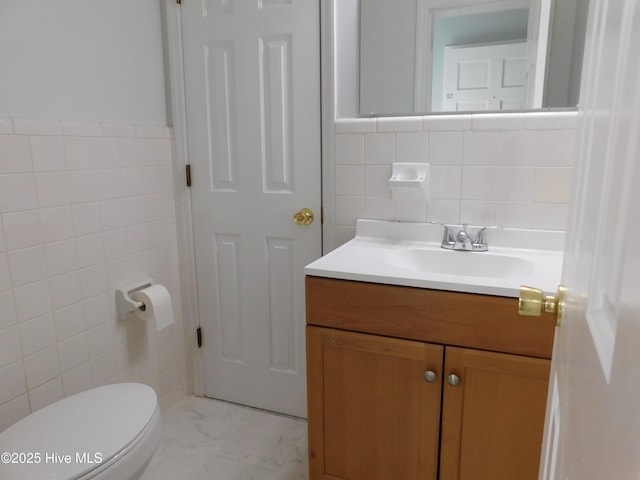 bathroom with vanity, toilet, and tile walls