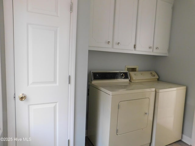clothes washing area with separate washer and dryer and cabinet space