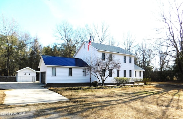 colonial-style house with metal roof, driveway, and an outbuilding