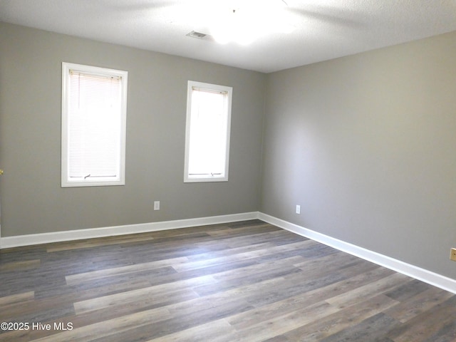 spare room with a textured ceiling and dark hardwood / wood-style flooring