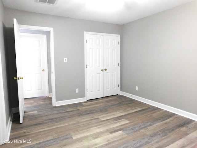 unfurnished bedroom featuring a closet, baseboards, and wood finished floors
