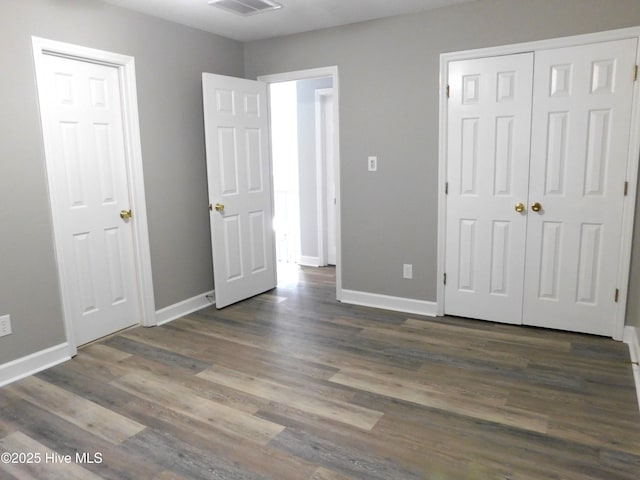 unfurnished bedroom featuring dark wood-type flooring, visible vents, and baseboards