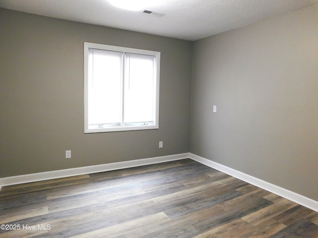 unfurnished room with dark wood-type flooring, baseboards, and visible vents