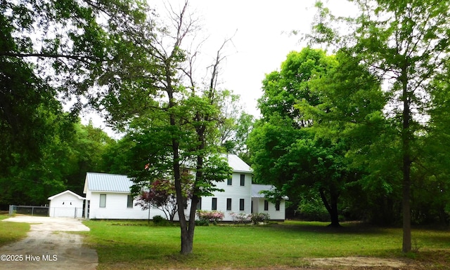 view of front of home featuring a front yard, an outdoor structure, metal roof, and concrete driveway