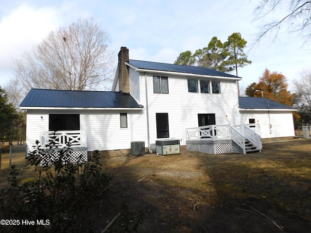 rear view of property featuring cooling unit, crawl space, metal roof, a chimney, and a deck