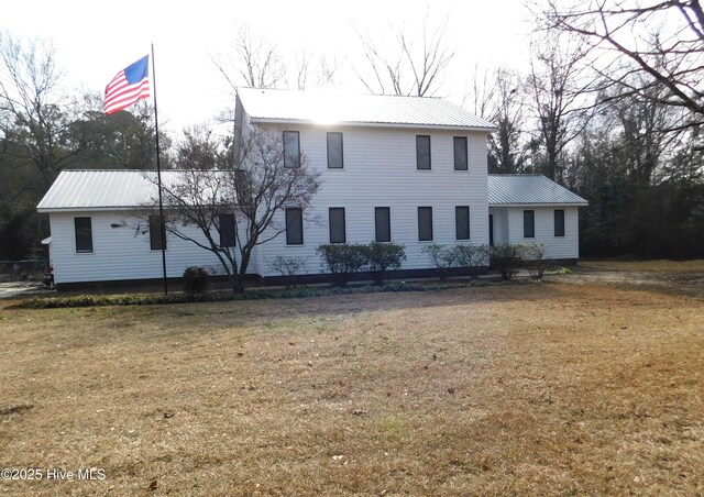 colonial-style house featuring metal roof and a front lawn
