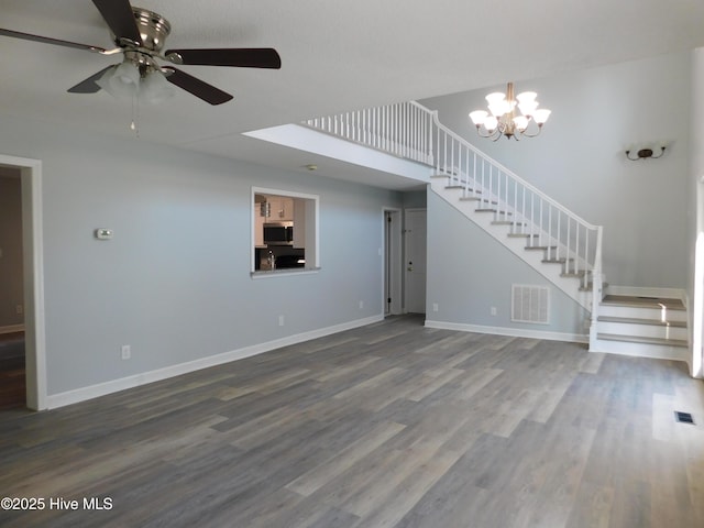 unfurnished living room with stairway, visible vents, dark wood-style flooring, and ceiling fan with notable chandelier
