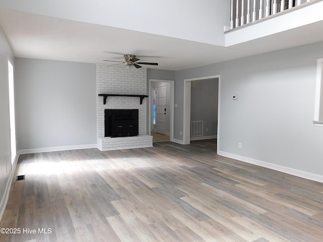 unfurnished living room with wood-type flooring, a fireplace, and ceiling fan