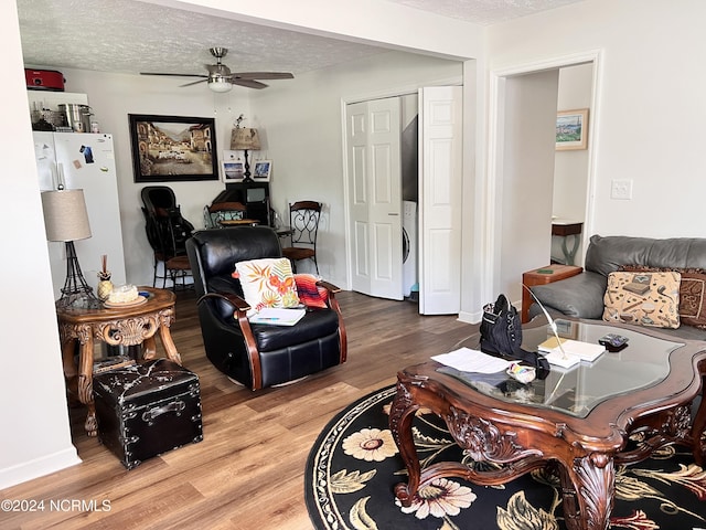 living room featuring ceiling fan, wood-type flooring, and a textured ceiling