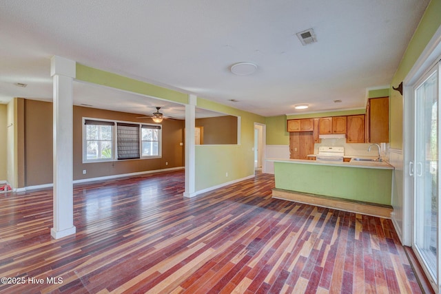 kitchen with white electric range oven, sink, dark hardwood / wood-style floors, kitchen peninsula, and decorative columns