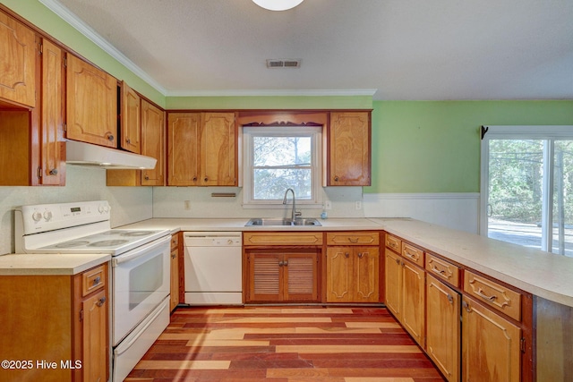 kitchen featuring sink, ornamental molding, kitchen peninsula, white appliances, and light hardwood / wood-style floors