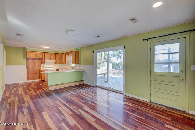 kitchen featuring dark hardwood / wood-style floors, sink, white range with electric stovetop, and kitchen peninsula