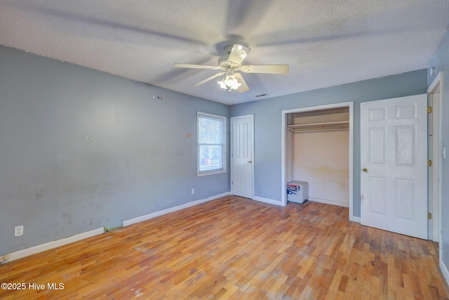 unfurnished bedroom with multiple closets, ceiling fan, light hardwood / wood-style flooring, and a textured ceiling