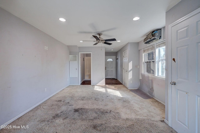 unfurnished bedroom with light carpet, an AC wall unit, and ceiling fan